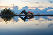 © mizuno555 - Young woman with long hair doing yoga early morning outdoor by the pool with sea view