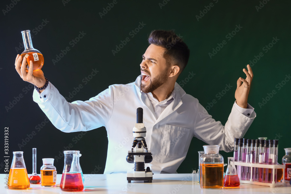 Crazy male alchemist with potions at table