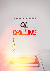 Poster - Conceptual hand writing showing Oil Drilling. Concept meaning involves the drilling and pumping of oil from underground wells Front view stacked books spiral note book on vintage wooden table