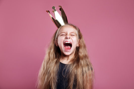 Shouting little girl in crown on pink background