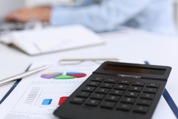 The black calculator lies on a chessboard. Background for calculating the business strategy calculation.