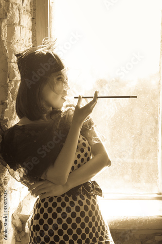 Fotografía Retro image of beautiful woman near window with mouthpiece