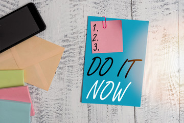 Conceptual hand writing showing Do It Now. Concept meaning not hesitate and start working or doing stuff right away Envelope paper sheet smartphone wooden vintage background