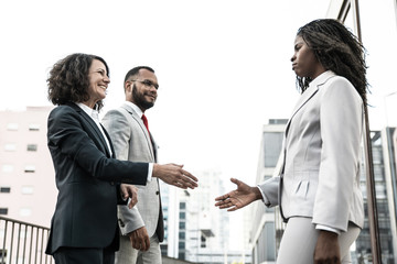 Wall Mural - Diverse businesspeople meeting near office building. Business man and women standing in city street and giving hands for handshake. Business meeting concept