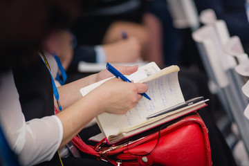 Russia, Krasnodar Territory, Anapa - March 23, 2017. Businesswoman writes in a notebook important information heard on the forum of personal growth.