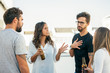 © Mangostar - Group of friends drinking beer, talking and arguing on outdoor terrace. Young men and women in casual meeting outside. Emotional talk concept