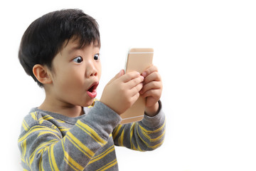 Amazed surprised funny little Asian boy using mobile phone with shocked expression, astonished kid playing video game on cellphone, children entertainment, indoor studio shot white background