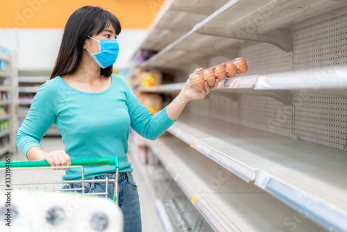 Cuadros en Lienzo Asian woman pick up last egg pack at Supermarket empty shelves amid COVID-19 coronavirus fears, shoppers panic buying and stockpiling toilet paper preparing for a pandemic