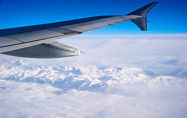 wing of airplane flying above clouds