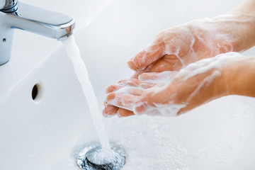 Wall Mural - Woman use soap and washing hands under the water tap. Hygiene concept hand detail.