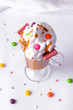 © Marharyta - caramel sweet dessert for children with cream decorated with sweets on a white background. vertical photo