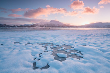 Wall Mural - Pink early morning glow light on snow covered mountains in arctic norway, super wide panoramic scene. Scenic winter view of snowy mountain in Scandinavia. Beautiful landscape concept background.