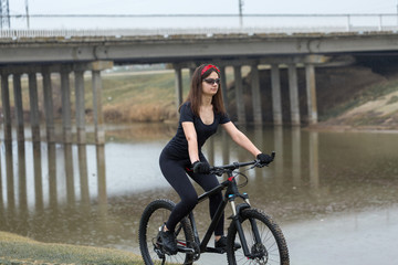 Girl on a mountain bike on offroad, beautiful portrait of a cyclist in rainy weather, Fitness girl rides a modern carbon fiber mountain bike in sportswear. Close-up portrait of a girl in red bandana.