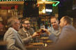 © AnnaStills - Group of businessmen holding glasses of beer and discussing some working moments in informal setting in the pub