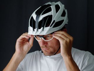 Close-up Portrait shot,  biker putting on a glasses and adjusting. Gray background..