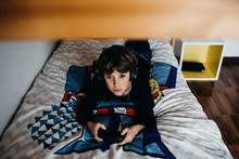 Boy Playing Video Games On The Bed In His Room