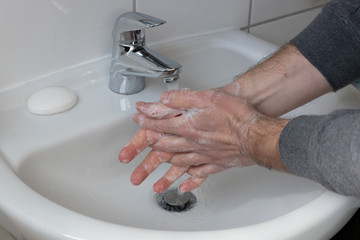 Wall Mural - Detail of a Young male washing his Hands with Soap under running water in order to reduce infection Risk during corona Virus pandemic