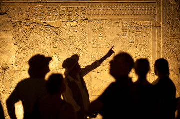 group of unrecognizable tourist archeologists standing in silhouette in front of ancient egyptian hi