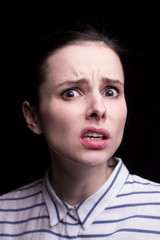 emotional girl in a striped shirt on a black background