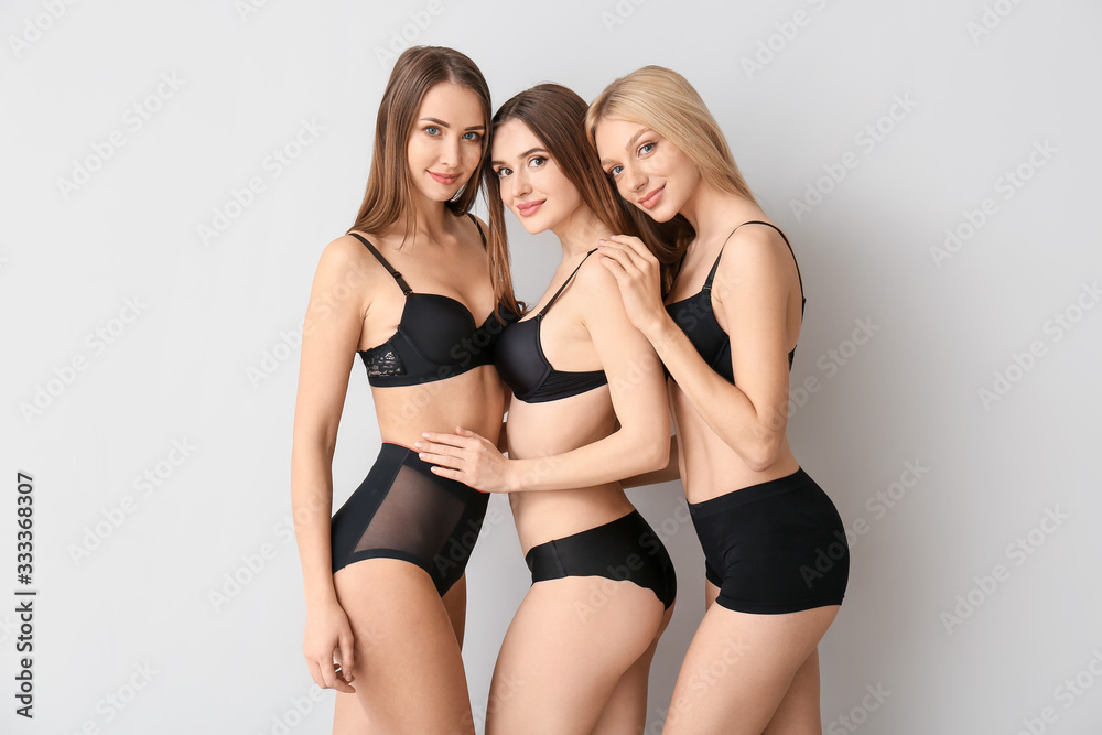 Beautiful young women in underwear on light background - obrazy, fototapety, plakaty 
