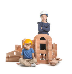 Little children dressed as builders playing with take-apart house on white background