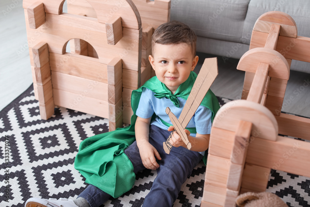 Little boy dressed as knight playing with take-apart house at home