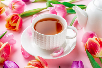 A cup of tea with tulips on rose background