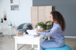 © Pixel-Shot - Woman sitting on fitness ball while working at home