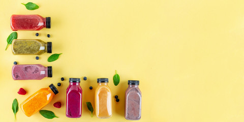 Wall Mural - Colourful healthy smoothies and juices in bottles on color background with copy space.