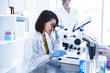 © Monet - 顕微鏡を覗く研究チームの女性