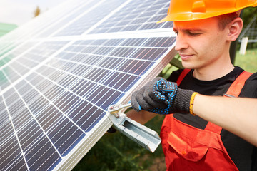 Wall Mural - Close up view of male worker installing the solar panels. Orange safety helmet on his head. Concept: renewable energy, technology, electricity, service, green power.