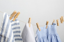 Different Kinds Of Clothes Drying On The Rope.Wooden Laundry Pegs, Rustic Rope, Blue Ad White Fabrics Hanging On The Rope