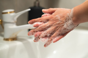  Person washing hands in the bathroom. Washing hands with soap and water for coronavirus prevention. Hand washing is the cornerstone of infection control. Stop spreading Covid-19