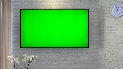 Watching TV with a remote control in hand. Green screen TV against a brick wall in the living room. Switch channels and sit at home to relax.