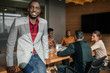 © JonoErasmus - Casual portrait of professional black african business man, coworkers hold a meeting in background