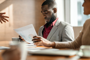 Candid close up shot of serious black african business man reading documents during a boardroom meeting