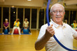 Anziano fa esercizio in palestra con i pesi