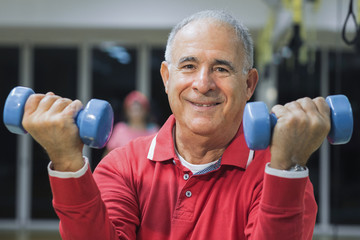 Anziano fa esercizio in palestra con i pesi