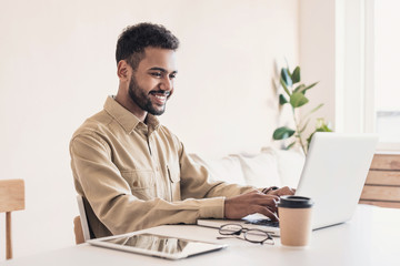Young handsome man using laptop at home, Businessman or student working online on computer indoors, Freelance, online marketing, distance education, home work and technology concept