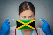 Coronavirus In Jamaica Female Doctor Portrait Hold Protect Face Surgical Medical Mask With Jamaica National Flag. Illness, Virus Covid-19 In Jamaica, Concept Photo