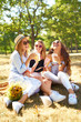 © maxbelchenko - Three beautiful young girls have fun together and drink fresh fruit juice in  hot summer day. Friends enjoying orange juice and  posing against the backdrop of the park. Summer concept.