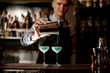© fesenko - Young barman professionally pours ready-made cocktail from shaker into glass.