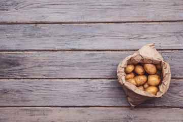 Wall Mural - A paper bag full of fresh homegrown potatoes on a wooden background