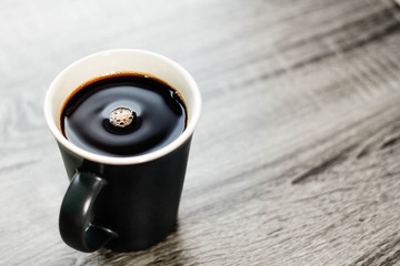 Cup of coffee with beans on wooden background