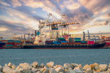 Logistics and container loading by large barges by sea in a harbor full of containers waiting to be transported