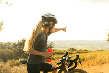 Female Cyclist Points Off Into Distance And Sunset