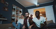 © vadim_key - Happy multiethnic male friends shout and cheer watching sports game together at home on TV using projector slow motion.