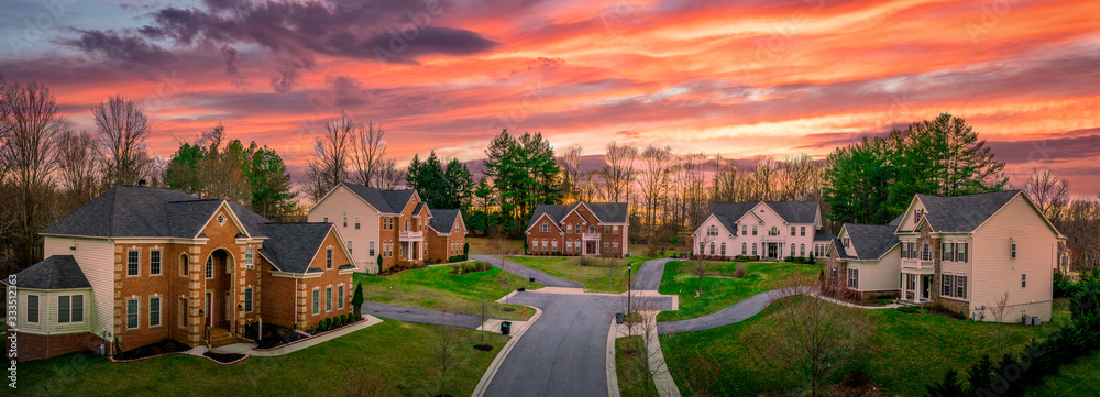 Neighborhood street sunset panorama of modern upper middle class single family houses American real estate in a new construction in Maryland USA colorful dramatic sky - obrazy, fototapety, plakaty 