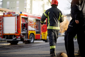 Fireman in uniform in front of fire truck going to rescue and protect. Emergancy servise concept.