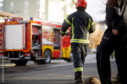 Photographie Fireman in uniform in front of fire truck going to rescue and protect